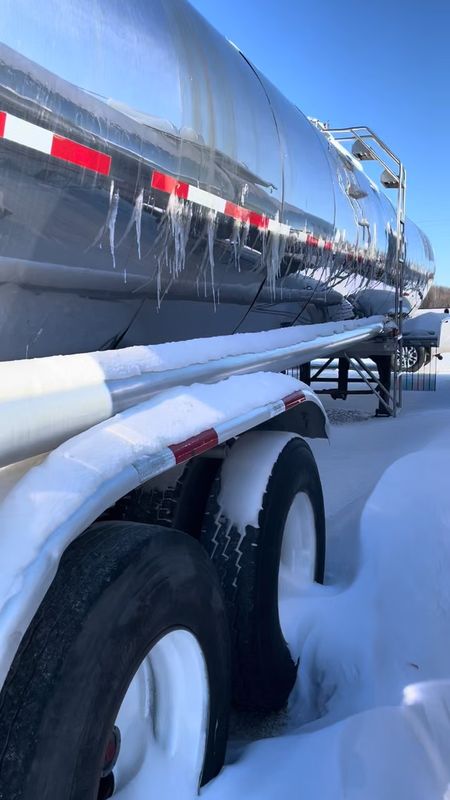 Icicles hanging from the side of the stainless tank, snow on the ground.
